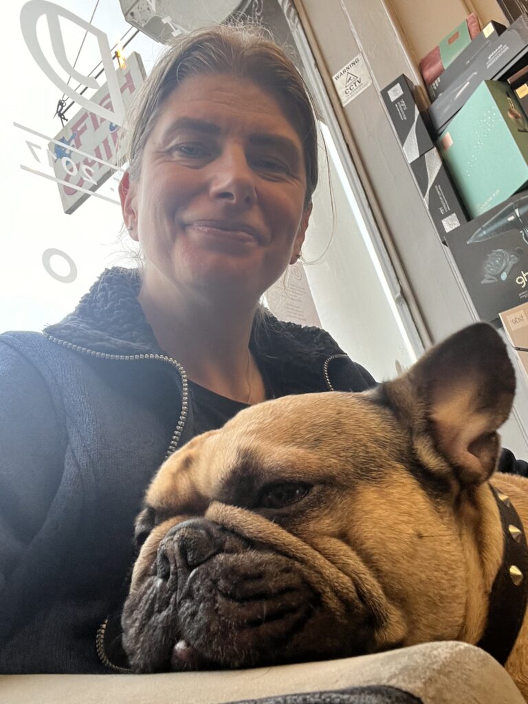 French bulldog having a snooze on owners lap in a hair salon.